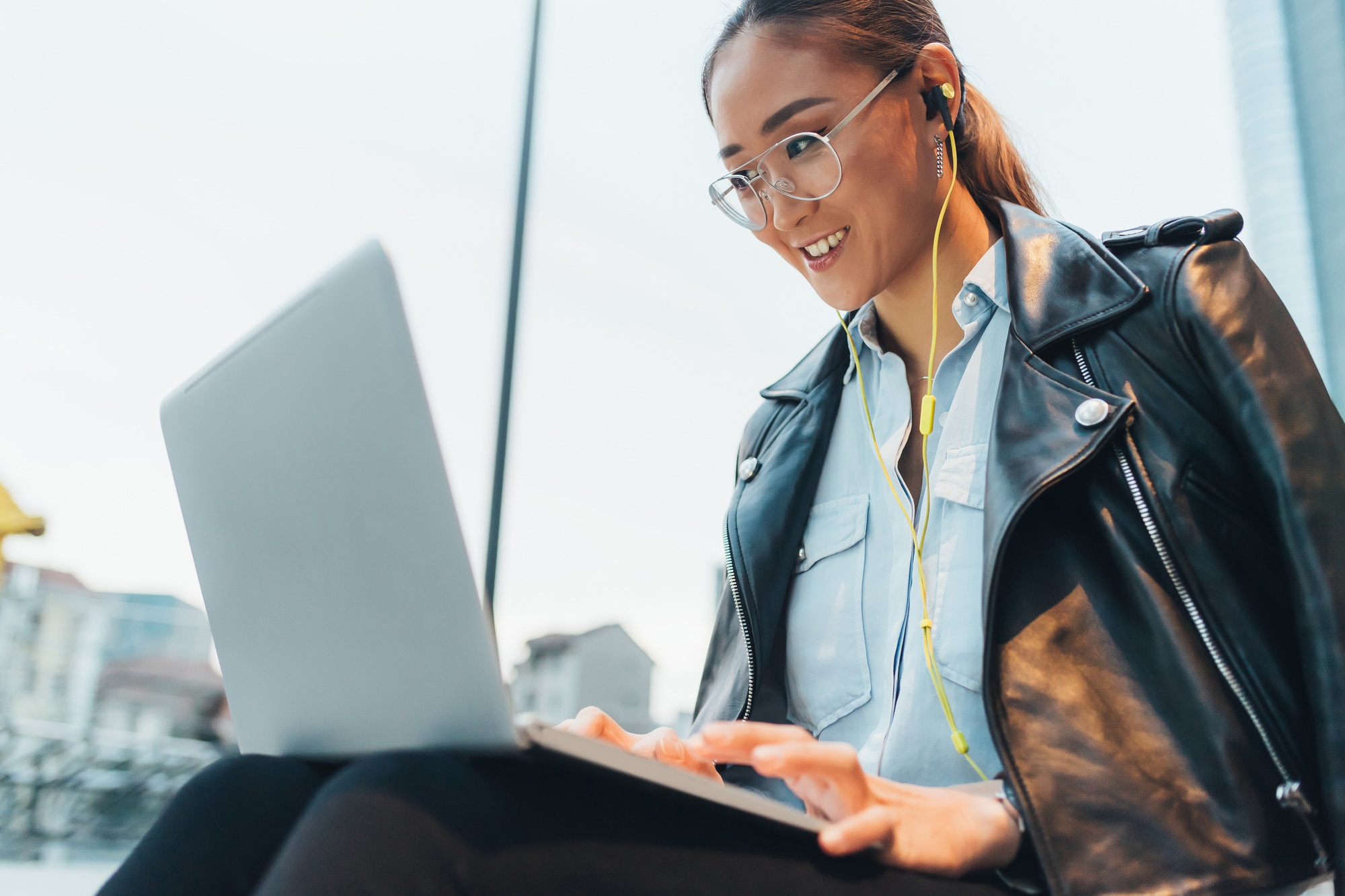 Businesswoman, sitting outdoors, using laptop, on video call, low angle view
